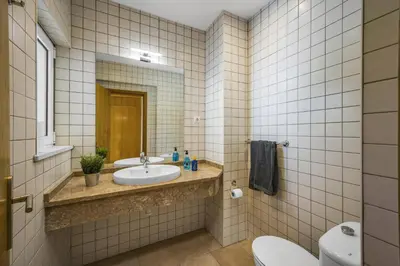a bathroom with a sink and a toilet and a mirror at Villa Falesia Blue by Villa Plus in Olhos de Água