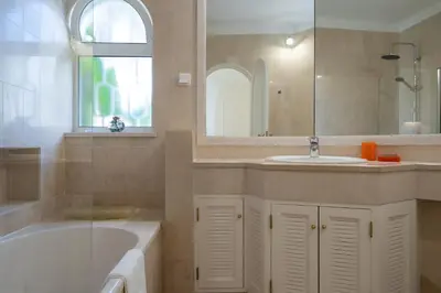 a bathroom with a tub and a sink and a mirror at Casa de Gales - Vilamoura in Vilamoura