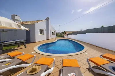 a swimming pool on a patio with chairs and a table at Villa Amendoeira by Villa Plus in Albufeira