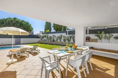 an outdoor patio with a white table and chairs at Villa Buganvillea by Villa Plus in Albufeira