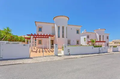 a large white house with a fence and a street at Villa Susana by Villa Plus in Albufeira