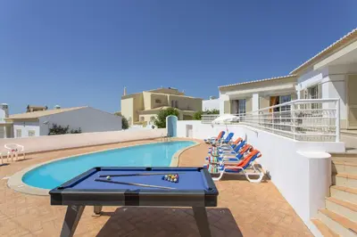 a pool with a ping pong table and chairs at Villa Primavera by Villa Plus in Albufeira