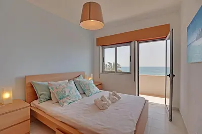 a bedroom with a bed with a view of the ocean at Quarteira Beach & Ocean View by Homing in Quarteira