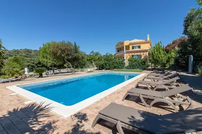 a swimming pool with lounge chairs and a house at Monte das Palmeiras in Loulé