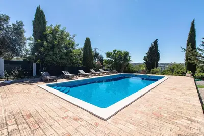 a swimming pool in a yard with chairs and trees at Monte das Palmeiras in Loulé