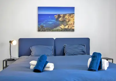 a blue bed with blue pillows and a view of the ocean at Sea View Apartment - 3 Swimming Pool & Fitness in Albufeira