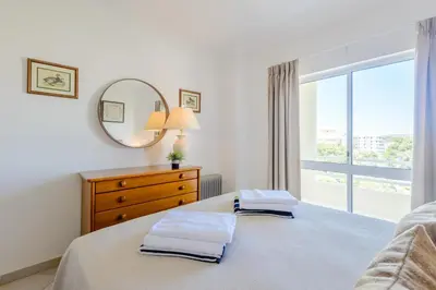 a bedroom with a bed with a dresser and a mirror at Casa Europa in Vilamoura