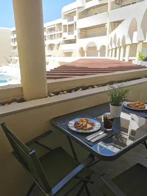 a table with a plate of food on a balcony at Apartamento T2 Palmeira Galé-Praia da Galé in Guia