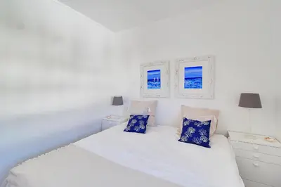 a white bedroom with a white bed with blue pillows at Apt 1 Quarto, Piscina, AC, Varanda, Prestige For Home in Vilamoura