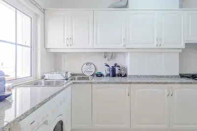 a white kitchen with white cabinets and a sink at Grevilias in Vilamoura