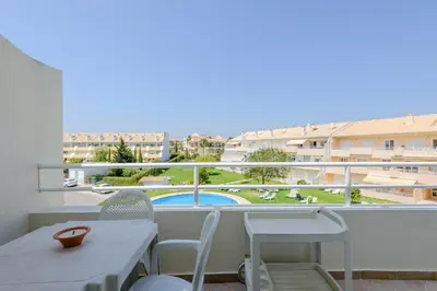 a balcony with a table and chairs and a view of a pool at Grevilias in Vilamoura