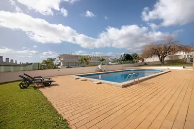 a villa with a swimming pool in front of a building at T1 Apartamentos Vista Alegre in Albufeira
