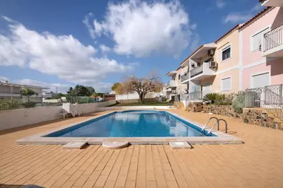 a swimming pool on a patio with a table and benches at T1 Apartamentos Vista Alegre in Albufeira