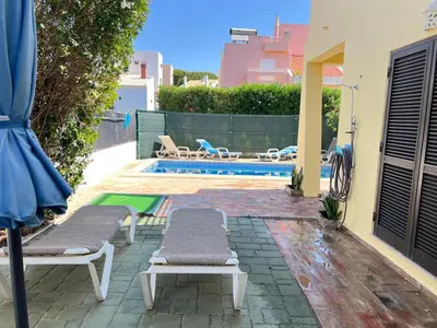 a swimming pool with two lounge chairs and an umbrella at Vila Sophia, Vilamoura- By Urbinvest Algarve in Vilamoura