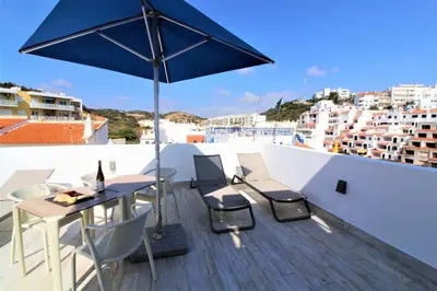 a patio with a table and chairs and an umbrella at Historic Centre C - Albufeira in Albufeira