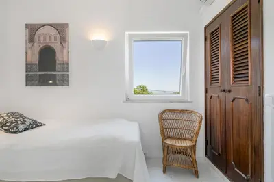 a bedroom with a bed and a chair and a window at Villa Saragoça in Loulé