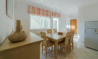 a kitchen with a table and chairs and a refrigerator at Villa 29 by Garvetur in Vale do Lobo