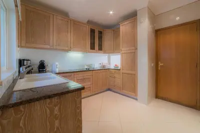 a kitchen with wooden cabinets and a sink at Villa 29 by Garvetur in Vale do Lobo