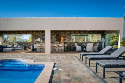 an outdoor dining room with a wooden table and chairs at Casa Rosa - Heated Pool & Sea Views in Loulé