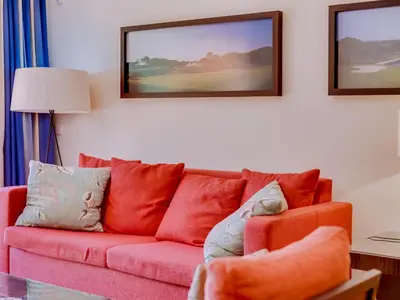 a living room with a pink couch and paintings on the wall at AL - Apartamento Vila Sol F5 P in Vilamoura