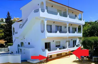 a white building with red chairs in front of it at AAA APARTAMENTS T0 Piscina Marina in Albufeira