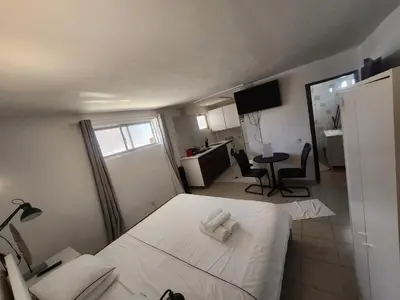 a bedroom with a white bed and a desk and a kitchen at AAA APARTAMENTS T0 Piscina Marina in Albufeira