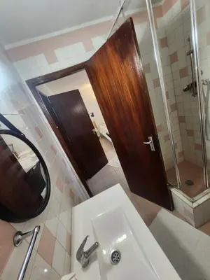 a bathroom with a sink and a wooden door at AAA APARTAMENTS T0 Piscina Marina in Albufeira