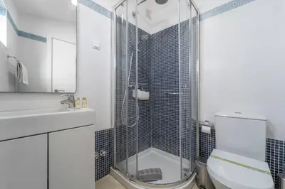 a bathroom with a shower with a toilet and a sink at Casa da Bateria by HelloVacations in Albufeira