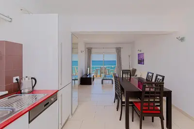 a kitchen with a table and a dining room with the ocean at Frente praia SIM T3 Praia Quarteira by HsRentals in Quarteira