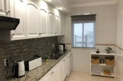 a kitchen with white cabinets and a sink and a window at Le Modern' in Albufeira