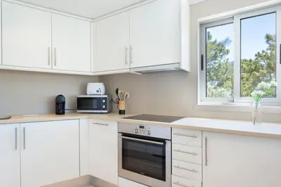 a white kitchen with white cabinets and a window at Varandas do Castelo By Garvetur in Albufeira