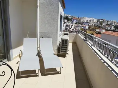 two white benches on a balcony with a view at De Hofnar Apartments Albufeira in Albufeira