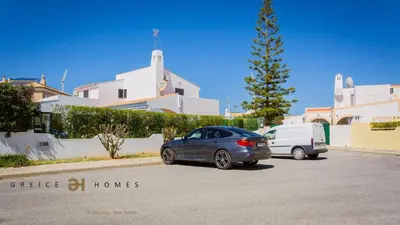 two cars parked in a parking lot in front of a building at Greice Homes-650 meters from the beach, 4 bedrooms villa for holidays in Vilamoura-Quarteira in Quarteira