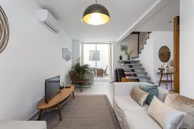 a living room with a white couch and a tv at Casa Lobo - 2 bedrooms - Duplex in Faro