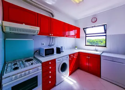 a kitchen with red cabinets and a washing machine at FLH Vilamoura Balcony with Pool in Vilamoura