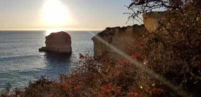 a sunset over the ocean with a rock in the water at 2 Terrace Town House in Albufeira
