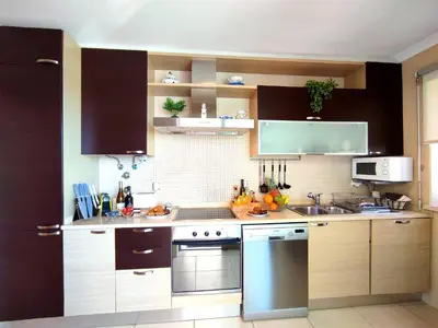 a kitchen with wooden cabinets and stainless steel appliances at Beach Condo with Atlantic Ocean View by BeCherish in Olhos de Água