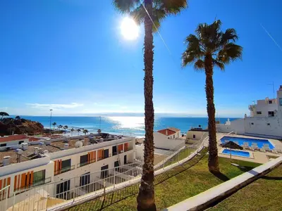 two palm trees and a building with the ocean in the background at Beach Condo with Atlantic Ocean View by BeCherish in Olhos de Água