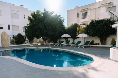 a hotel with a pool and a umbrella and chairs at Apartamentos Julieta in Albufeira