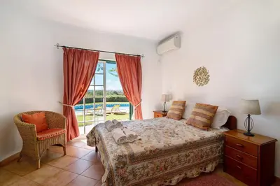 a bedroom with a bed and a window and a chair at Casa do Barrocal in Almancil