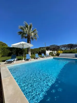 a swimming pool with chairs and an umbrella at Vila Castelo in Vale do Lobo