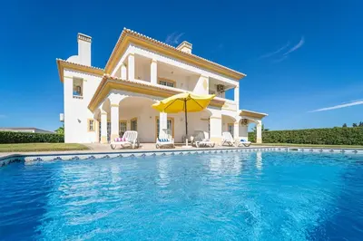 a villa with a swimming pool in front of a house at Filomena Golf Paradise in Guia