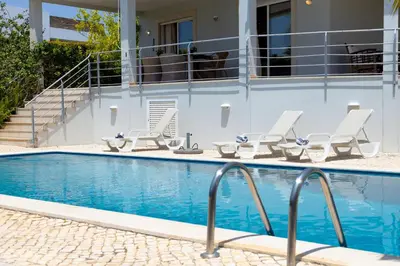 a swimming pool with lounge chairs next to a building at Villa Sara in Quarteira