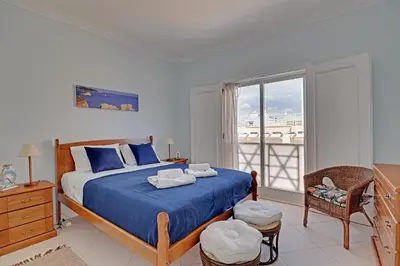 a bedroom with a bed with blue sheets and a window at Vilamoura Main Avenue by Homing in Vilamoura