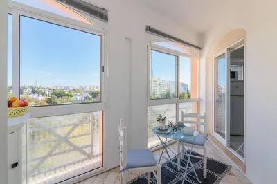 a room with windows and a table and chairs at Vilamoura Main Avenue by Homing in Vilamoura
