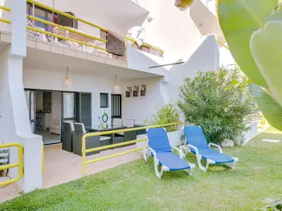a patio with two blue chairs and a kitchen in a house at AL - Apartamento Sunrise, Sol Nascente 1 Ground floor in Vilamoura