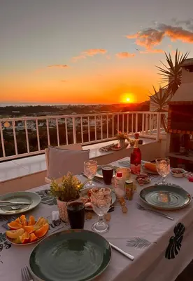 a table with plates of food on a balcony with the sunset at Ocean View Skyline Apartment ‚Hakuna Matata‘ in Albufeira