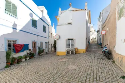 a cobblestone street with white buildings and a scooter parked on the side at Typical Fisherman's Cottage with amazing sea views! in Albufeira
