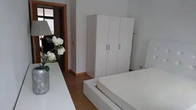 a white bedroom with a vase with flowers in it at Faro City Center Apartment I in Faro