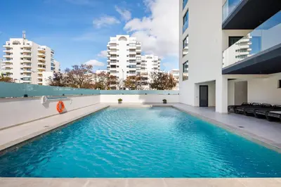 a swimming pool in the middle of a building with tall buildings at Apartamento Porlamar in Quarteira